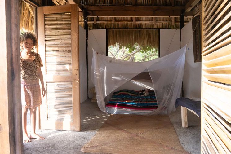 Innenansicht einer Hütte in Mazunte mit Moskitonetz über dem Bett und Kind im Eingang