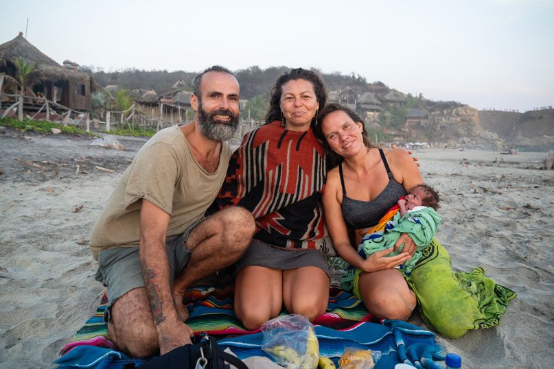 Familie mit Neugeborenem auf einer Decke am Strand von Mazunte
