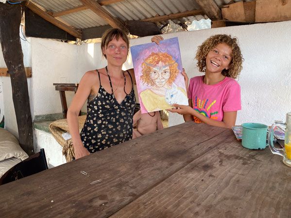 Zwei Mädchen halten ein buntes Portraitbild in einer offenen Hütte in Mazunte