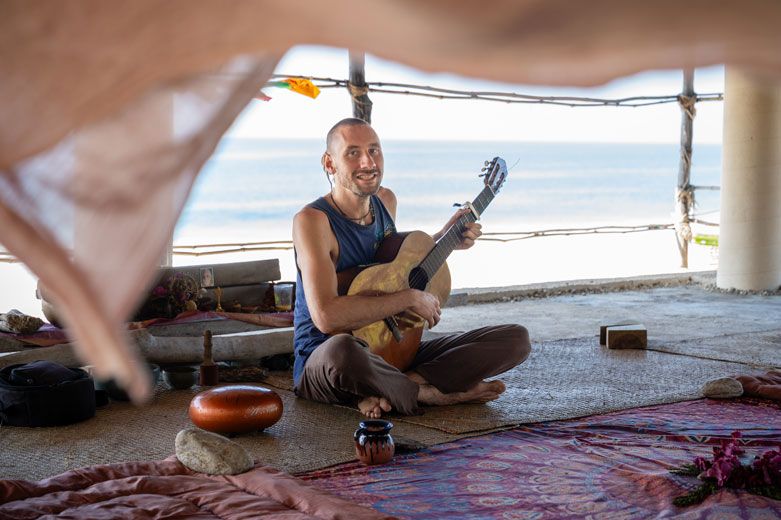 Mann spielt Gitarre in einer offenen Hütte mit Blick aufs Meer in Mazunte